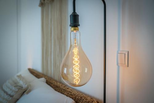 eine Glühbirne über einem Bett in einem Zimmer in der Unterkunft Apartamento situado no centro histórico da cidade in Setúbal