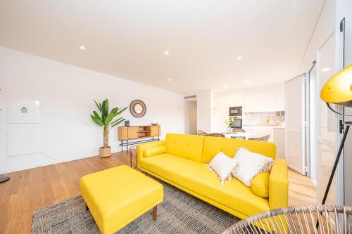 a yellow couch in a living room with a kitchen at Apartamento situado no centro histórico da cidade in Setúbal