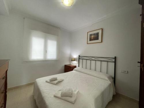 a bedroom with a bed with two towels on it at Aires de Regla, Apartamentos Living Sur in Chipiona