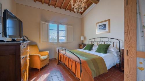 een slaapkamer met een bed, een tv en een bank bij Scorpione in Gaiole in Chianti