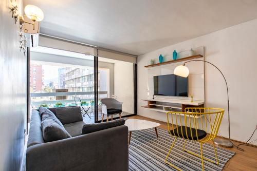 ein Wohnzimmer mit einem Sofa und einem TV in der Unterkunft Apartment - El Golf - Costanera Center in Santiago