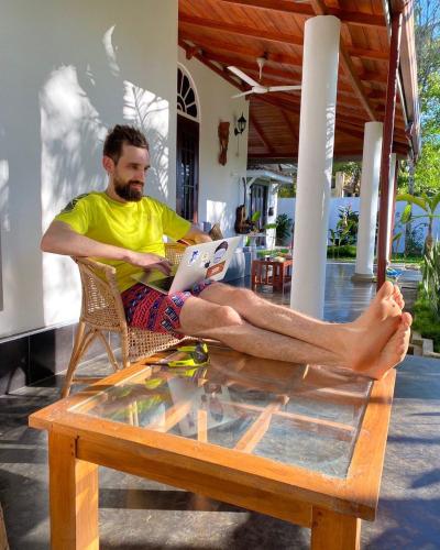 a man sitting on a table reading a book at Villa Ali in Galle