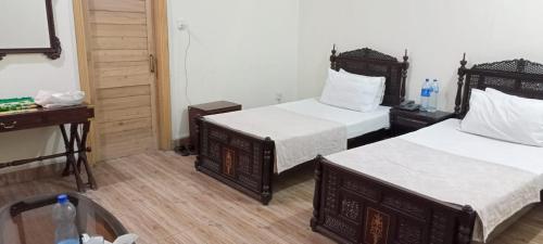 a hotel room with two beds and a desk at Luxury Palace Peshawar in Peshawar