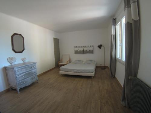 une chambre avec un lit, une commode et un miroir dans l'établissement La Bastide Saint Jacques, à Vinsobres