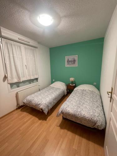 two beds in a room with green walls and wooden floors at Les Myrtilles in Thann