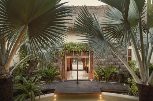 a courtyard with palm trees and a wooden walkway at Hotel Ma'xanab Tulum in Tulum