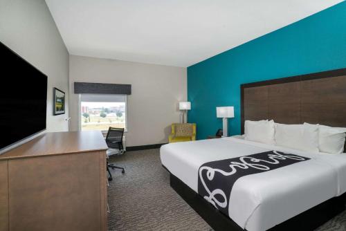 a hotel room with a large bed and a desk at La Quinta by Wyndham West Memphis in West Memphis