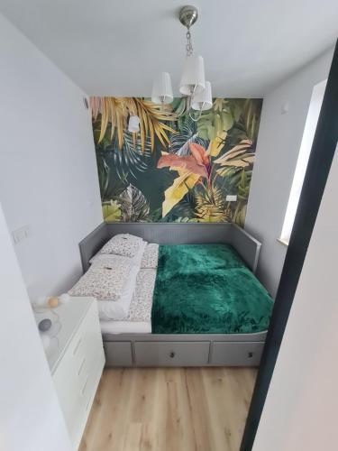 Apartament Sosnowa في بووافي: غرفة نوم بسرير وبطانية خضراء