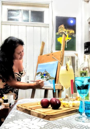 a woman painting a painting on an easel at Hst Ateliê Marli Marques in Pelotas