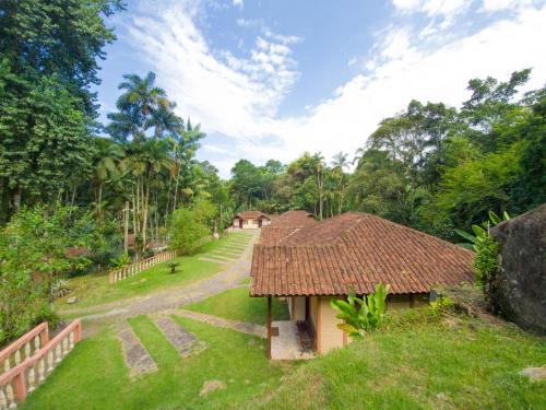 a small house with a thatched roof in a field at Pousada Canto do Curió Paraty in Paraty