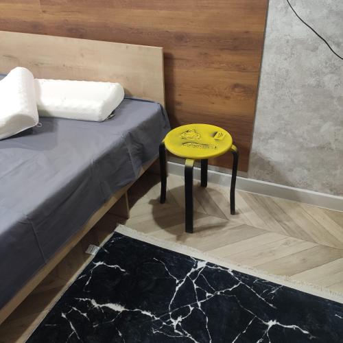 een gele kruk naast een bed in een kamer bij ВИП квартира in Oral