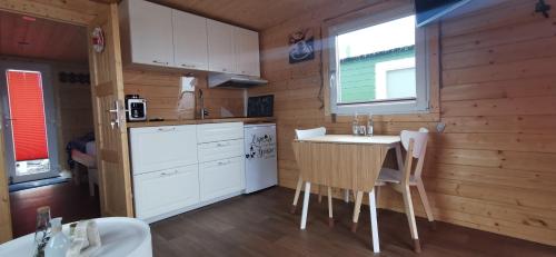a kitchen with white cabinets and a table and chairs at Hausboot Wilhelmshaven - Traum Unterkunft an der Jade in Wilhelmshaven