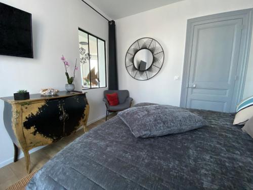 a bedroom with a bed and a mirror and a chair at LES EMBRUNS in Fécamp