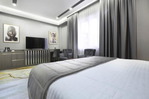 a bedroom with a bed and a desk and a television at Bourbon Boutique Hotel in Yerevan