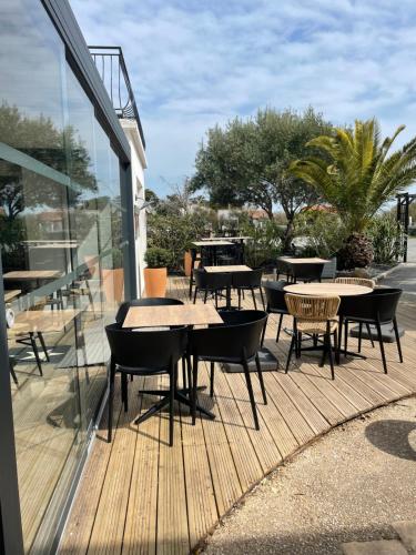 a patio with tables and chairs on a wooden deck at Hôtel Le Martray in Ars-en-Ré