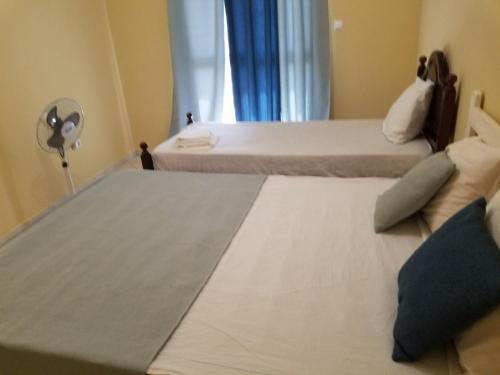 two beds in a small room with a fan at chez albino guest house in São Filipe