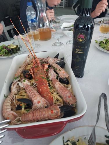 a plate of seafood and pasta on a table with a bottle of wine at Hotel Restorant Genti Peshkatari in Orikum