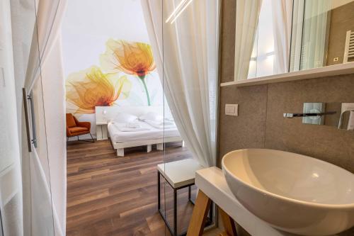 a bathroom with a sink and a room with a bed at Hotel Baia Azzurra - Lake Front in Nago-Torbole