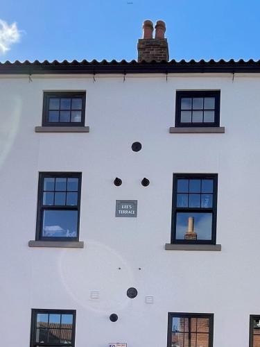 a white building with black windows and a chimney at Lees Lookout Holt ,2 bedroom luxury apartment with private parking in Holt