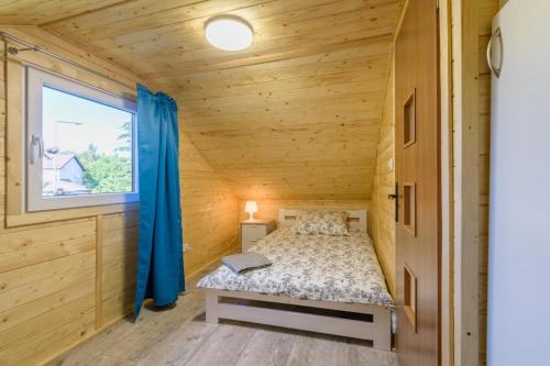 1 dormitorio en una cabaña de madera con cama y ventana en Domki Piamola Kąty Rybackie en Kąty Rybackie