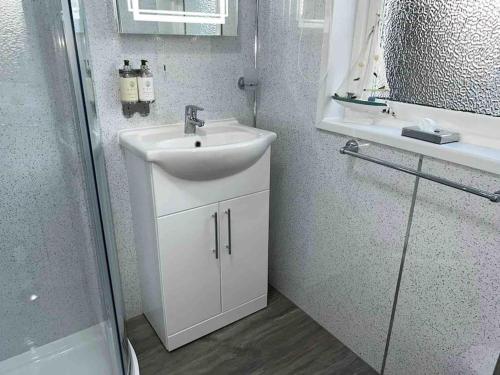 Baño blanco con lavabo y espejo en Modern 2 Bed Apartment, en Oban
