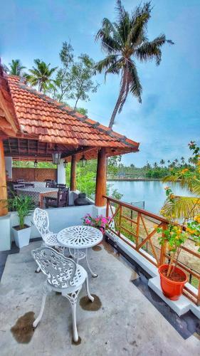 a patio with a table and chairs and a view of the water at Vala House in Cherai Beach