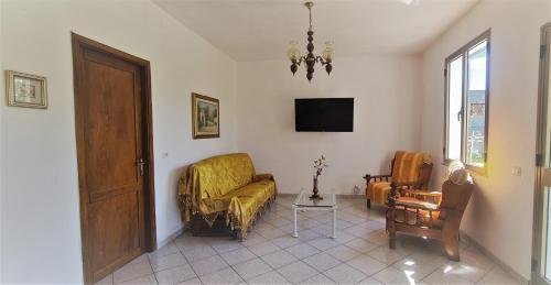 sala de estar con sofá, silla y TV en Cosy home with private parking near by sea en Siniscola