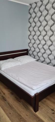 a bed with a white mattress on a wooden floor at Apartament Panoramiczna in Kielce