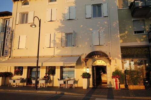 a person sitting at a table outside of a building at Hotel Europa in Desenzano del Garda