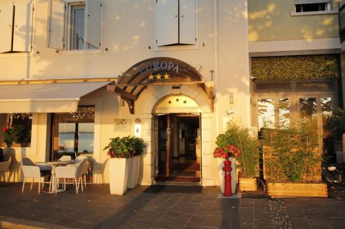 un ristorante con tavoli e sedie di fronte a un edificio di Hotel Europa a Desenzano del Garda