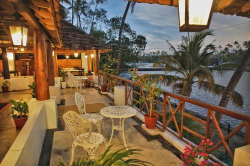 a patio with tables and chairs and a view of the water at Vala House in Cherai Beach
