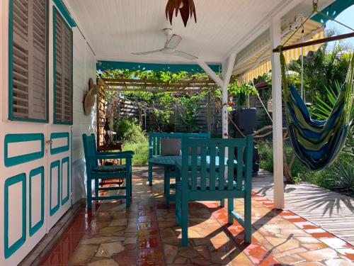 a porch with chairs and a table and a hammock at Villa Maracoudja in Sainte-Anne