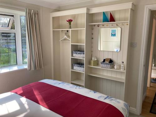 Schlafzimmer mit einem Bett, einem Spiegel und Regalen in der Unterkunft The Nest in Modbury