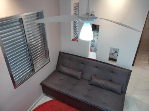 a living room with a couch and a ceiling fan at Apartamento Lindíssimo e Moderno próximo a praia in Praia Grande