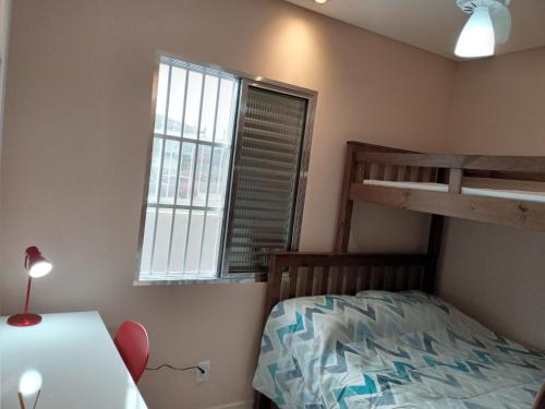 a bedroom with a bunk bed and a desk at Apartamento Lindíssimo e Moderno próximo a praia in Praia Grande