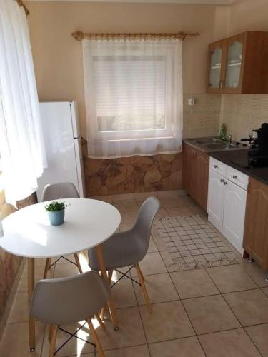 a kitchen with a table and chairs and a white table at Bellis - Apartmanok in Szilvásvárad