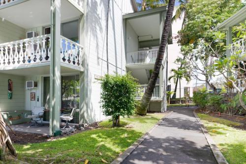 a white building with a balcony and a sidewalk at Kona Islander Inn # 219 in Kailua-Kona