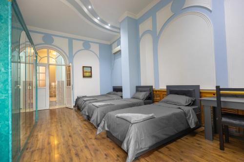 a room with four beds with blue walls and wooden floors at New Friends Mini-Hotel in Tashkent