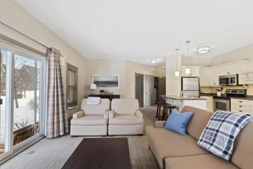 a living room with a couch and chairs and a kitchen at Blue Mtn Getaway in Historic Snowbridge Chalet in Collingwood