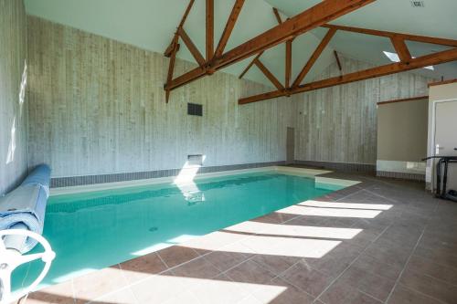 a large swimming pool with blue water in a room at Chambres d'hôtes La Roche in Saint-Hilaire-des-Landes