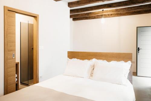 a bedroom with a white bed with a wooden headboard at Grad Štanjel House in Štanjel