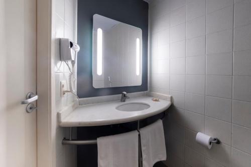 a bathroom with a sink and a mirror and towels at ibis Sao Jose do Rio Preto in Sao Jose do Rio Preto