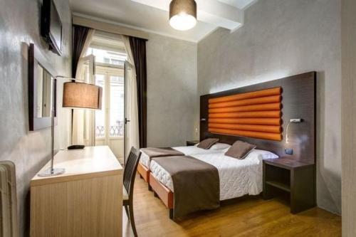 a bedroom with a bed and a desk with a lamp at The One Firenze in Florence