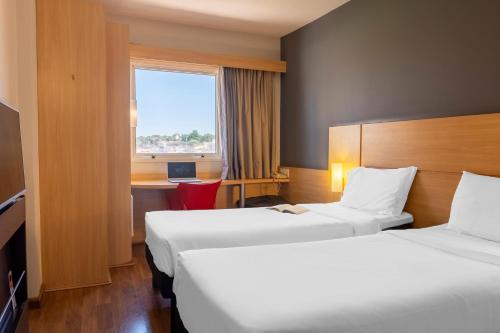 a hotel room with two beds and a window at ibis Sao Jose do Rio Preto in Sao Jose do Rio Preto