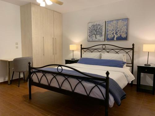 een slaapkamer met een bed, een bureau en 2 lampen bij Petra Nova Villas in Mochlos