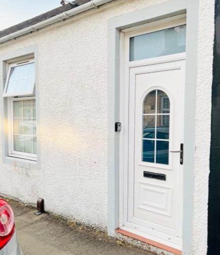 a white door on the side of a white building at Gardiner Cottage in Prestwick