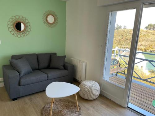 a living room with a couch and a table and a balcony at Appartement T3 vue mer Sauzon balcon et parking privé in Sauzon
