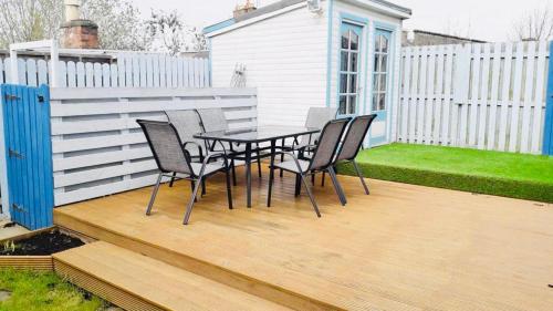 a patio with a table and chairs on a wooden deck at Gardiner Cottage in Prestwick