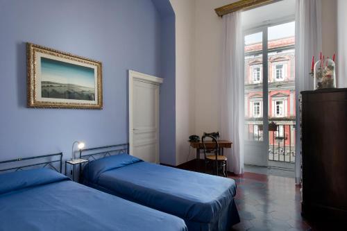 een blauwe kamer met 2 bedden en een raam bij Domus Decumana in Napels