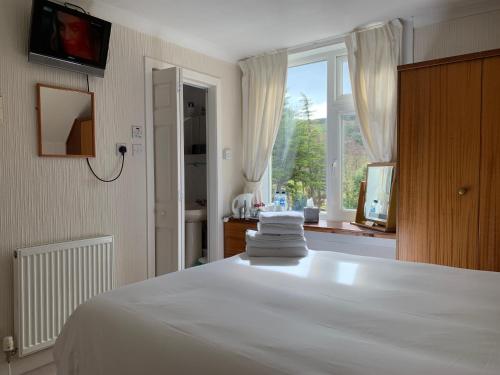 a bedroom with a white bed and a window at Allandale House in Brodick